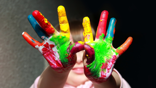 Bērna rokas, ar krāsām nokrāsotas plaukstas un pirksti 