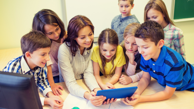 Skolotāja ar bērniem skatās planšetē
