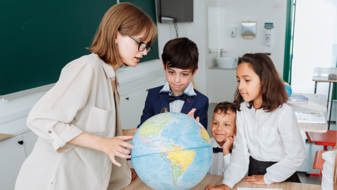 Skolotāja kopā ar bērniem pie globusa