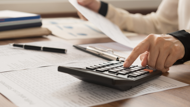 Tuvplānā kalkulators, cilvēks rēķina un trā rokā tur lapu