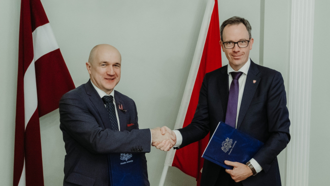 Uz Latvijas un Šveices karoga fona Šveices Konfederācijas vēstnieks Martēns Mišlē un Finanšu ministrijas valsts sekretāres vietnieks ES fondu jautājumos Armands Eberhards spiež viens otram roku