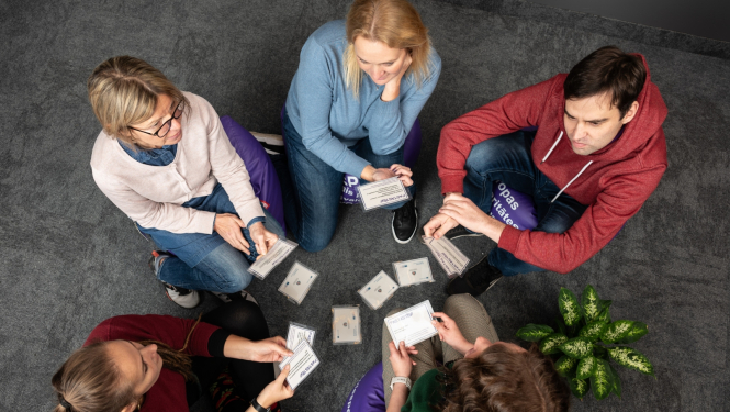 Skats no augšas: četras sievietes un viens vīrietis sēž uz sēžammaisiem un sarunājas