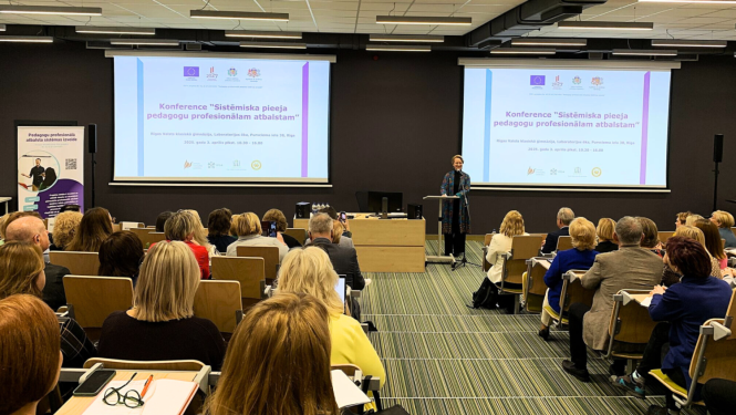 Cilvēku grupa sēž un klausās konferenci. Konferenci atklāj izglītbas un zinātnes ministre Dace Melbārde.