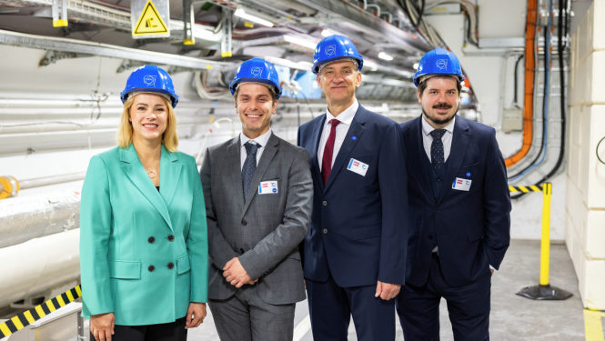 Premjerministre Evika Siliņa un citi Latvijas delegācijas pārstāvji zilās kiverēs stāv CERN telpās.