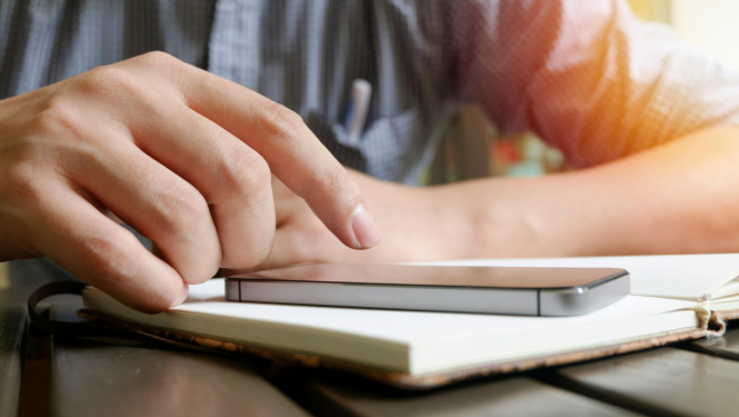 Cilvēks spiež uz telefona ekrāna