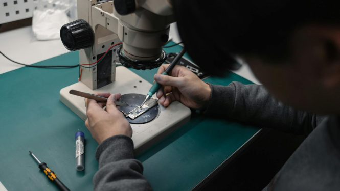 Cilvēka rokas zem mikroshēmas lodē mikroshēmu