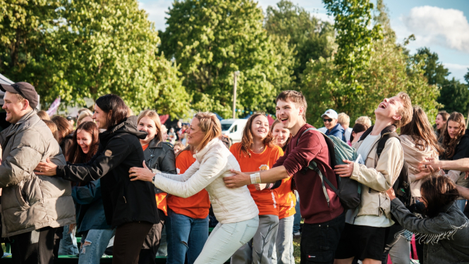 Priecīgi jaunieši spēlē spēli, kurā ar rokām turas viens pie otra 