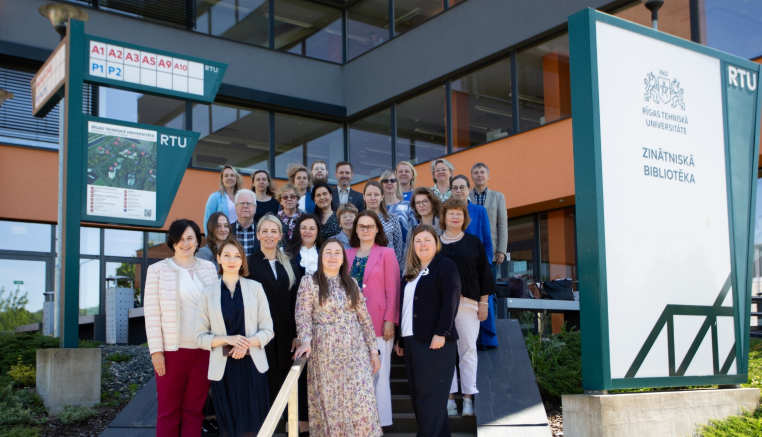 Semināra dalībnieki stāv uz kāpnēm