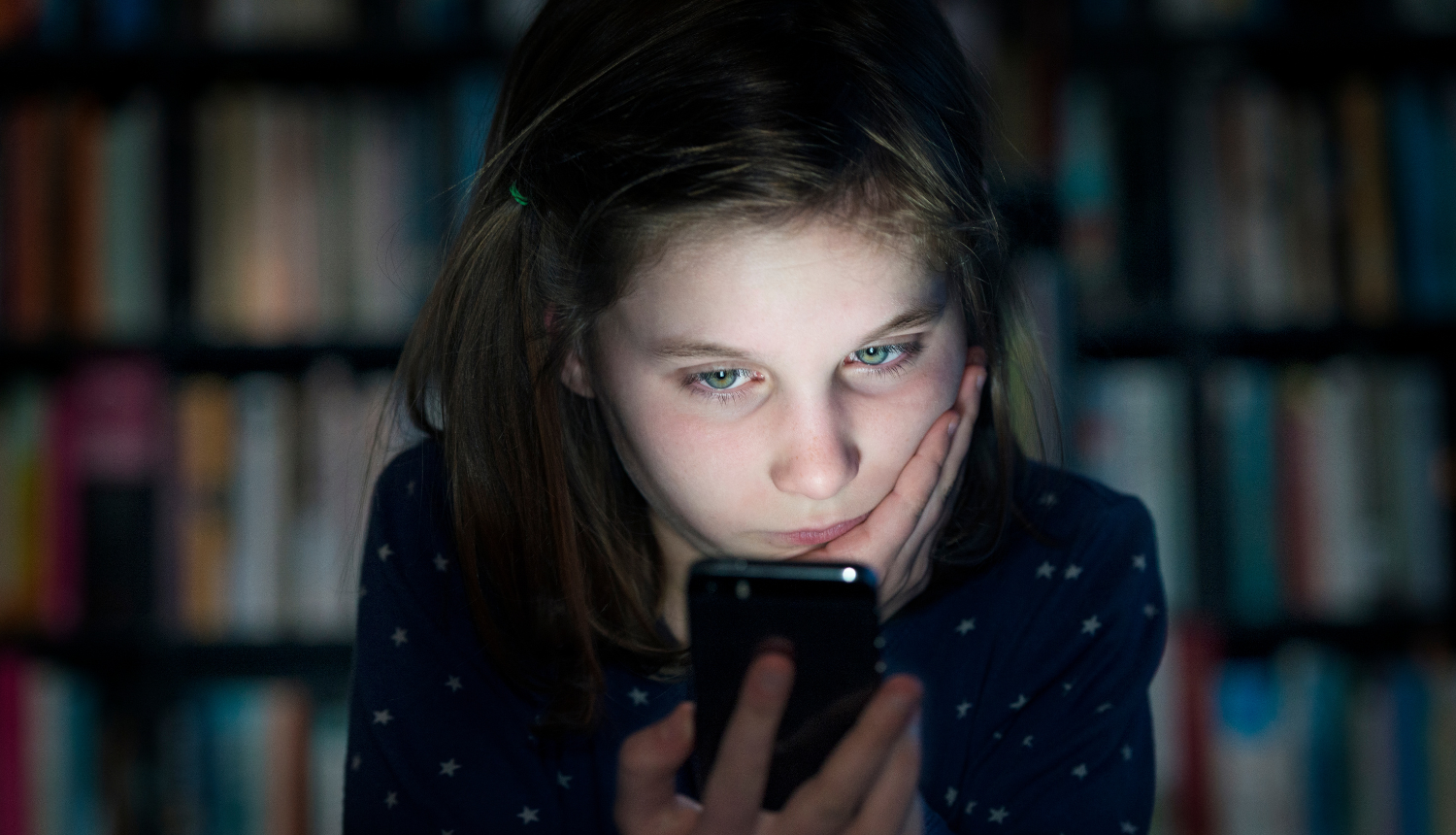 Tumsā meitene skatās telefona ekrānā