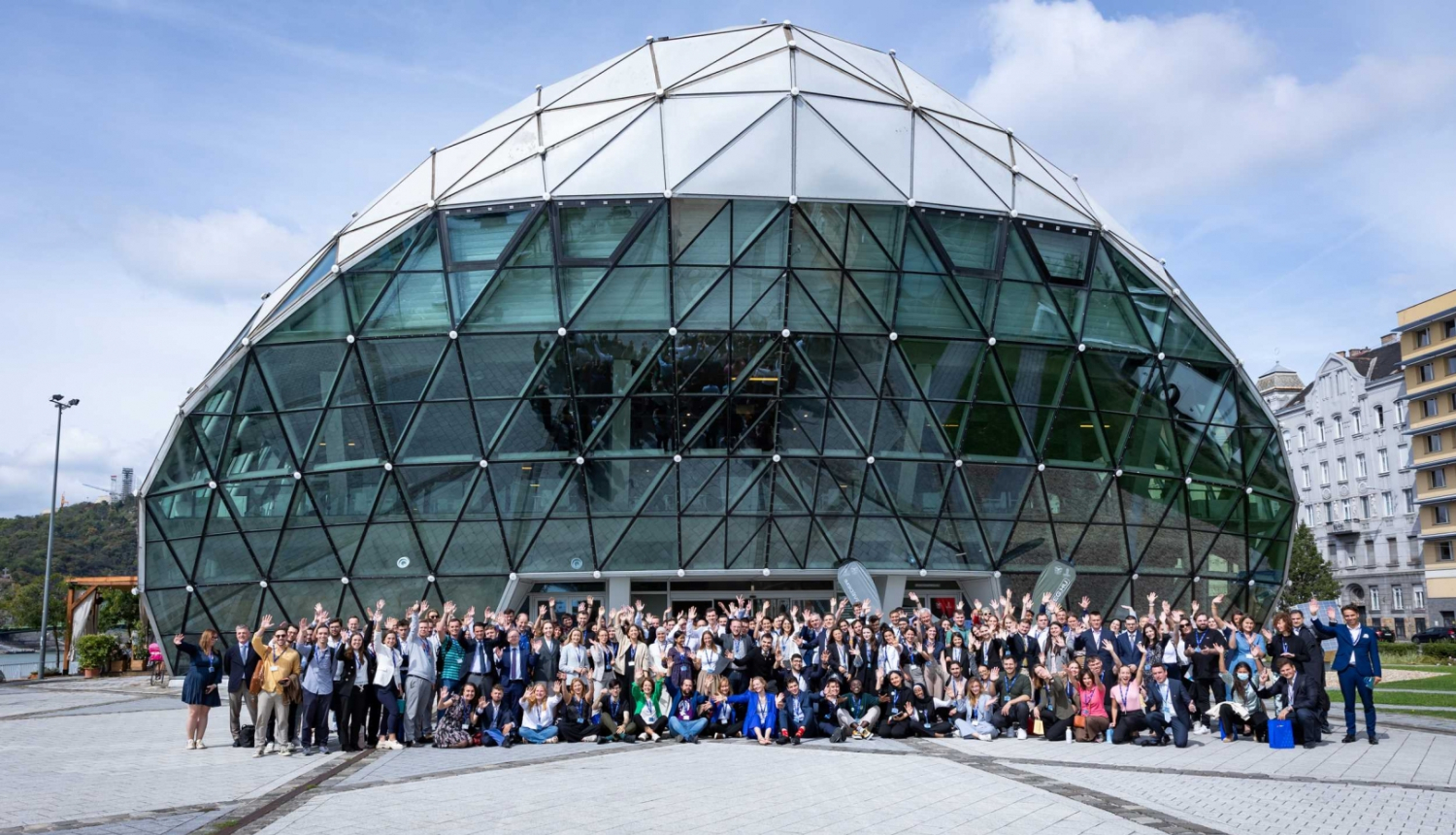 Eiropas Jaunatnes konference Budapeštā. Dalībnieku kopbilde pie pasākuma norises vietas. Norises vietas ēka ir stiklots kupols.