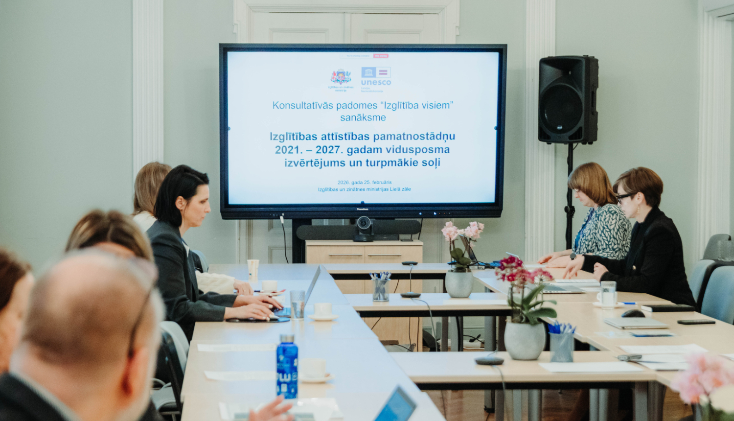 Sanāksmes dalībnieki, fonā redzams prezentācijas titulbilde