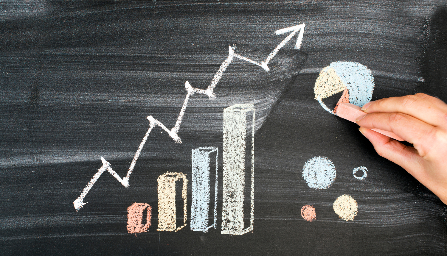 Ar krītiņiem uz tāfeles uzzīmēts augošs grafiks un bulta uz augšu