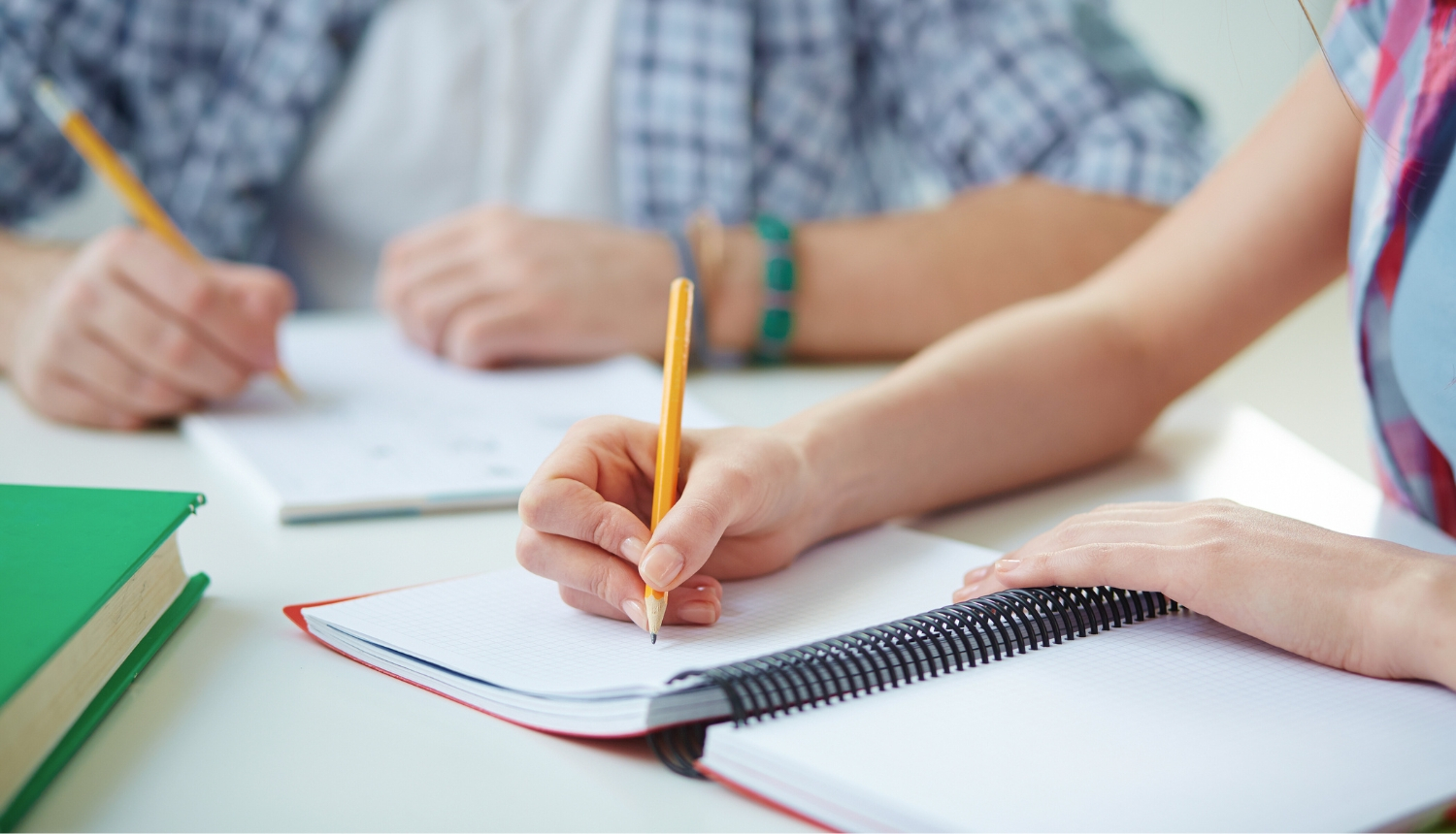 Jaunieši ar pildspalvu pieraksta burtnīcās piezīmes