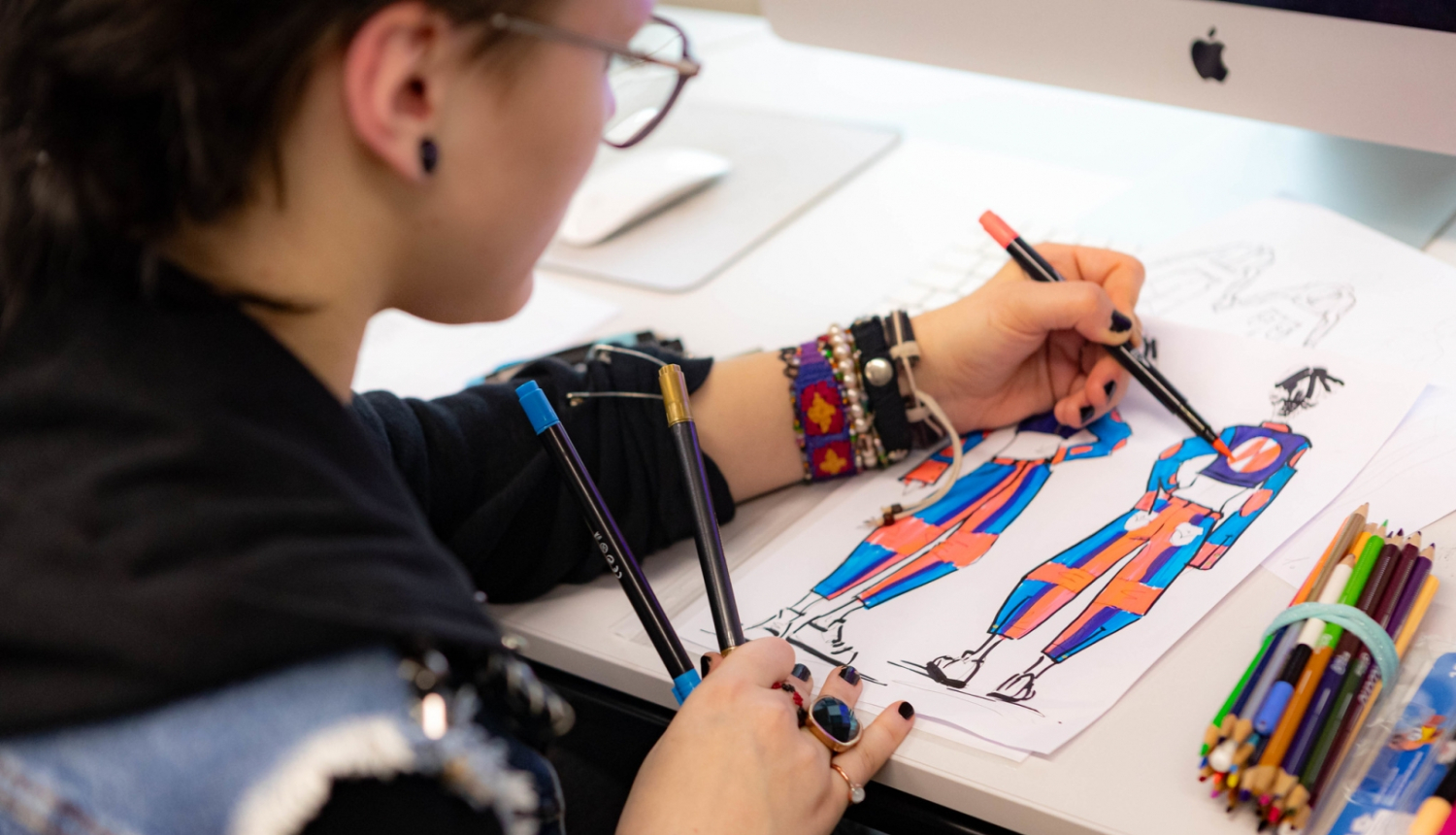 SkillsLatvia konkursa pusfinālā meitene zīmē tērpu skices
