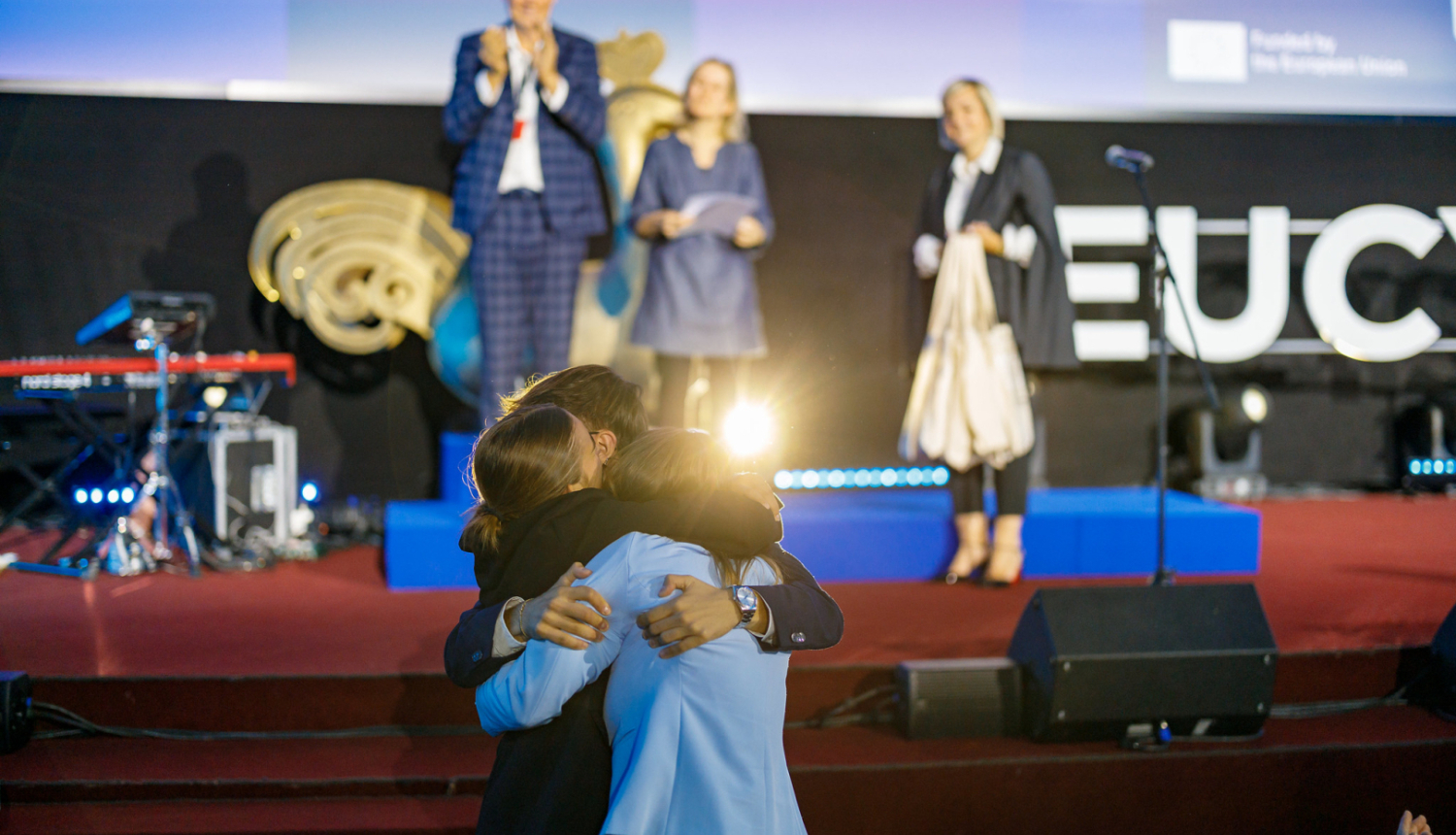 Cilvēki apskāvušies pie EUCYS 2025 skatuves