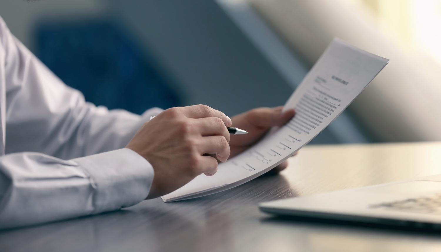 Cilvēks tur rokās dokumentu un pildspalvu.