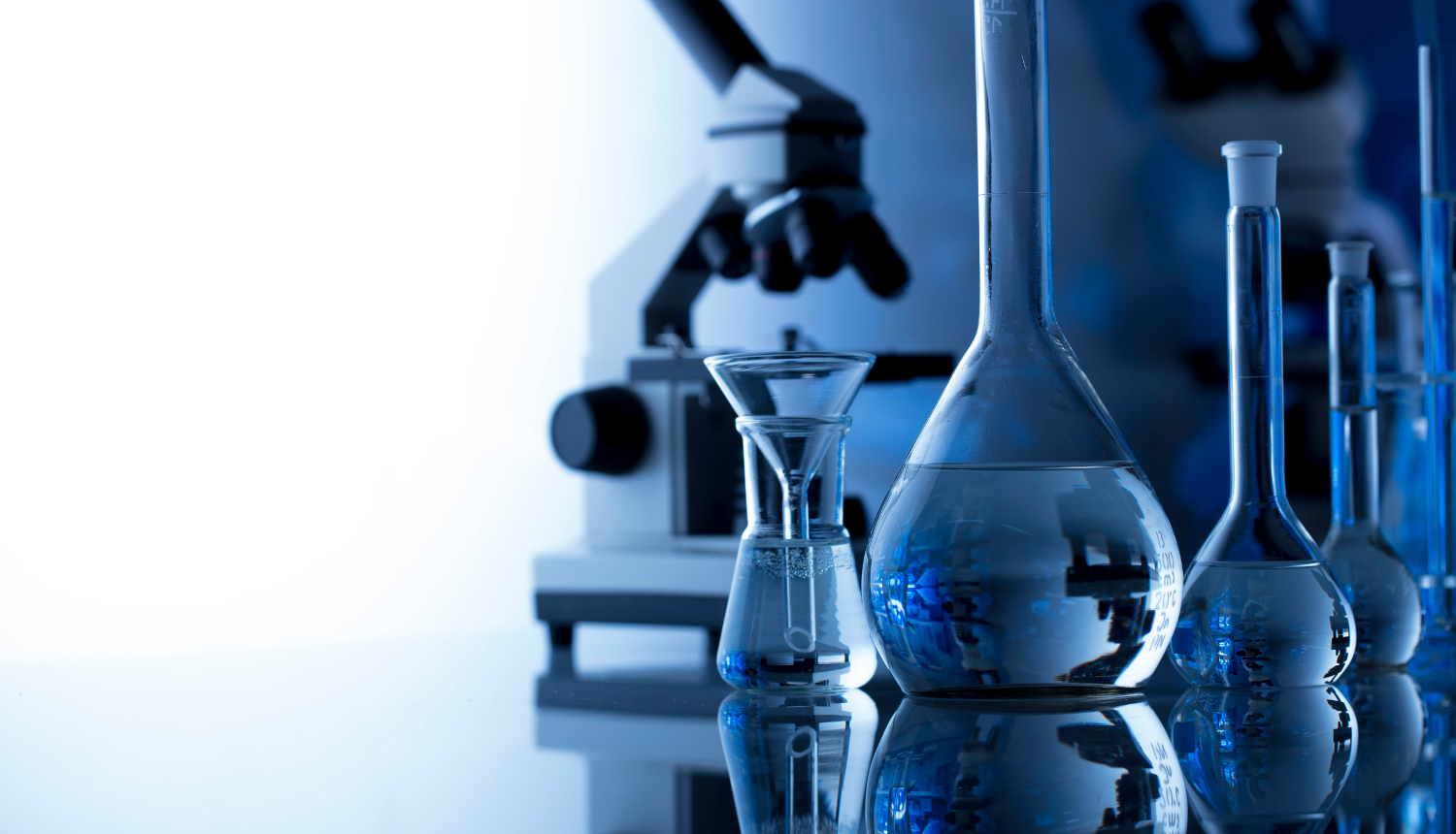 Uz galda stāv mēģenes un mikroskops