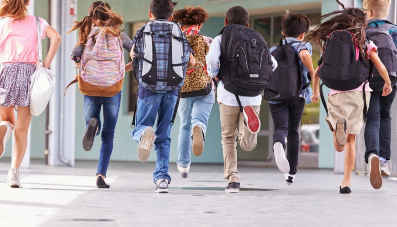 Skolēni ar mugursomām skrien uz skolu