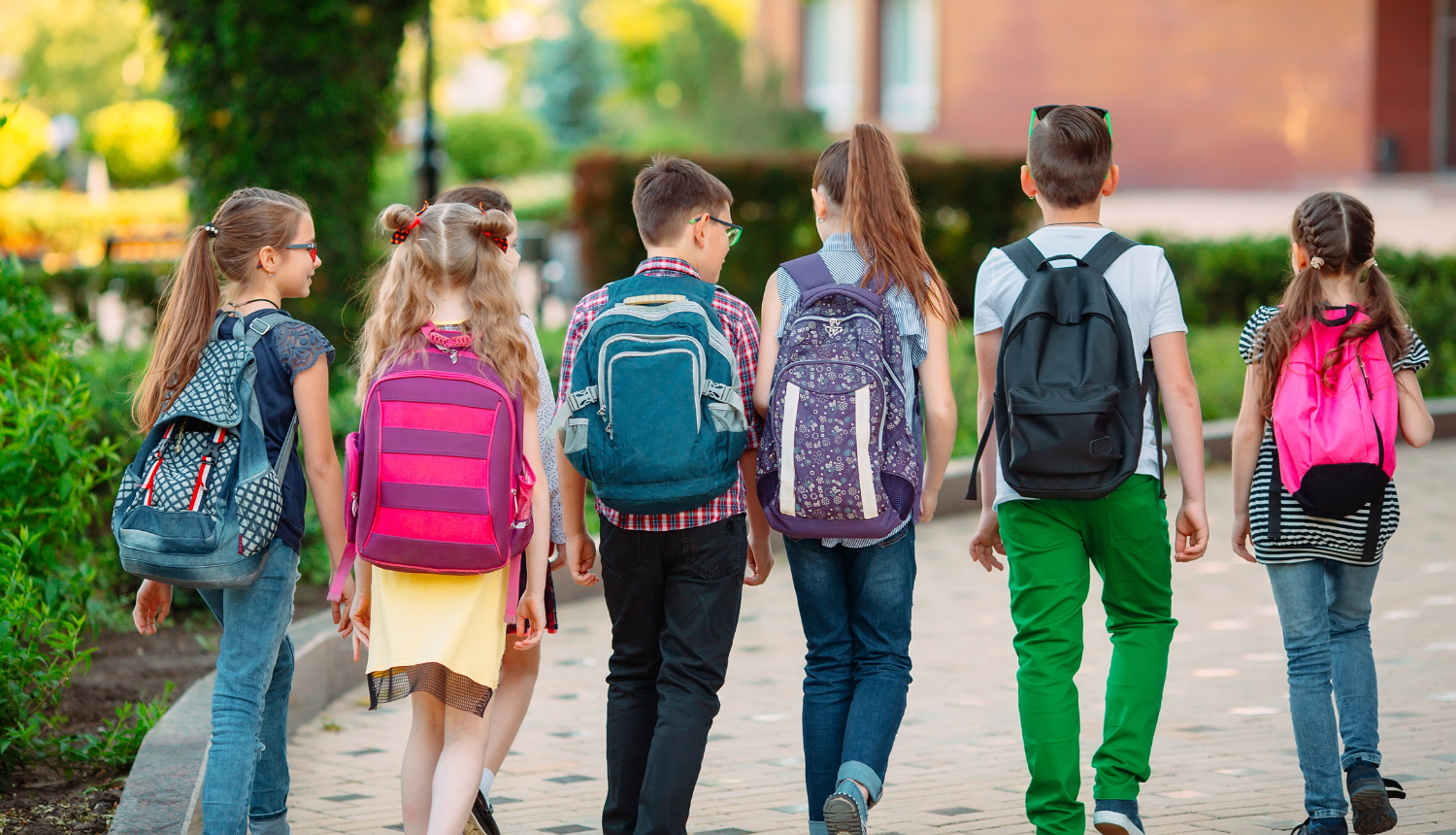 Skolēni ar mugursomām iet uz skolu.