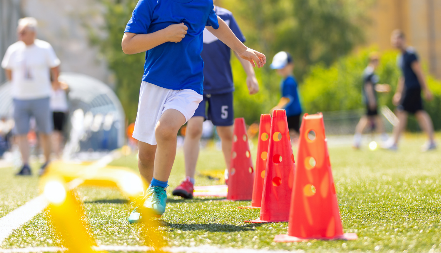 Bērni skrien stafeti futbola laukumā