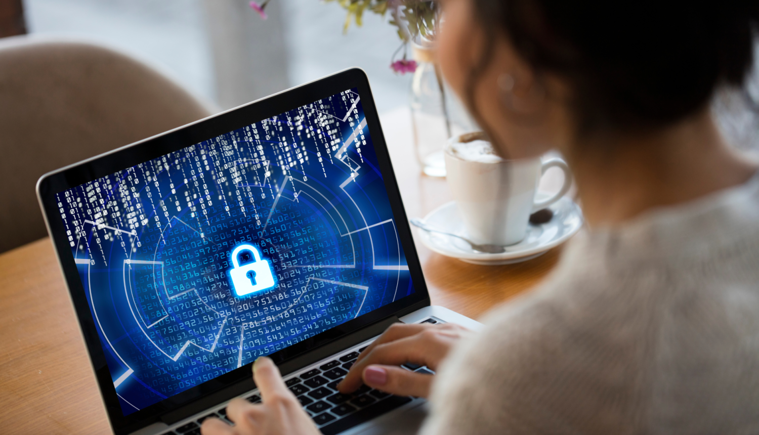 Sieviete pēta datoru, datorā redzams kiberdrošības elements