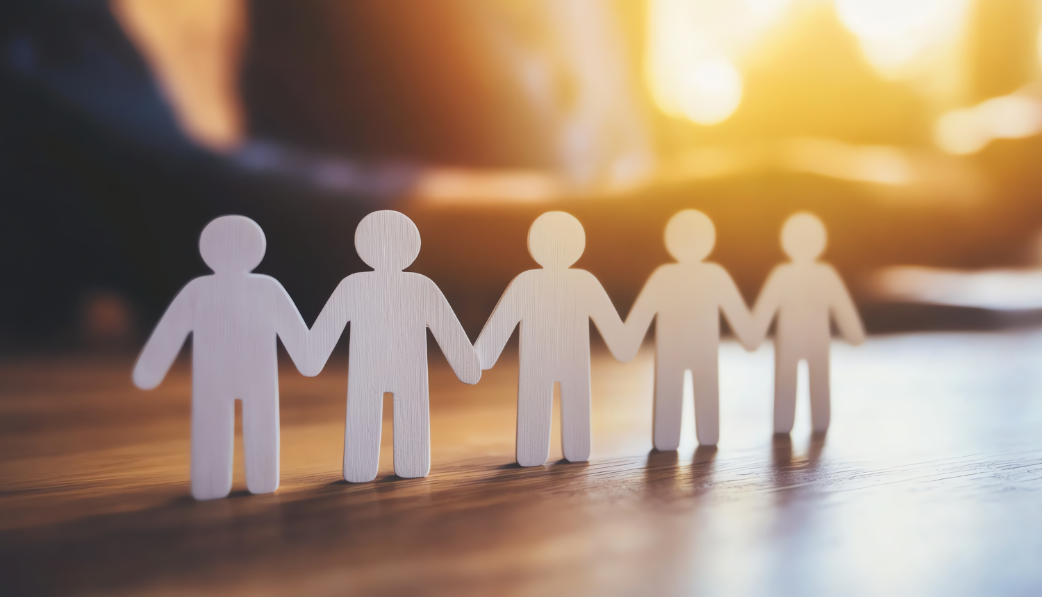 Papīra cilvēciņi sadevušies rokās, nolikti uz galda