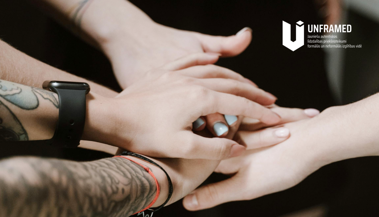 Kopā saliktas rokas. "UNFRAMED" logo