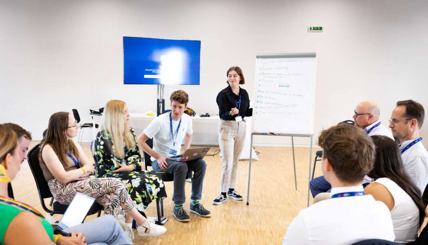 Cilvēki sēž aplītī un apspriežas. 