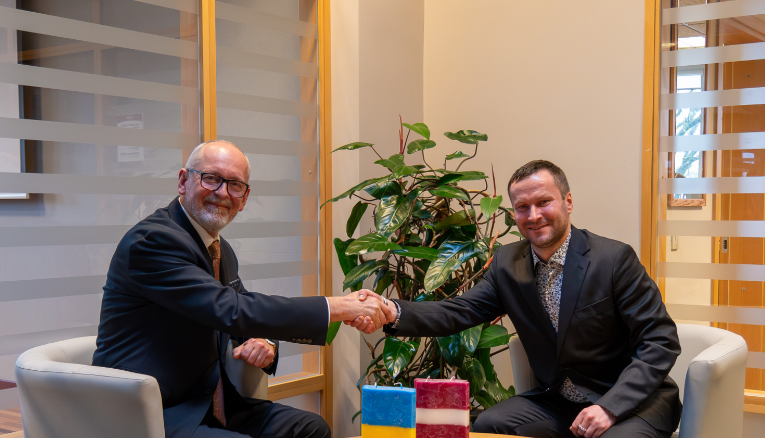 Rīgas Stradiņa universitātes rektors Aigars Pētersons un Latvijas Sporta pedagoģijas akadēmijas rektors Kalvis Ciekurus spiež viens otram roku 