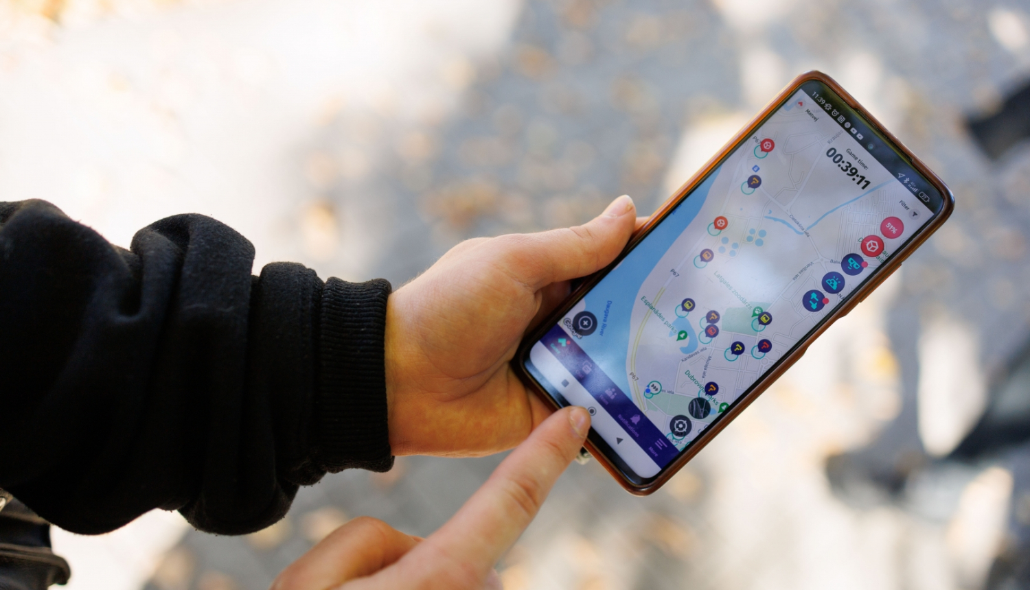 Jaunieša rokas tur rokās telefonu, kura ekrānā ir karte ar atzīmētiem apskates objektiem