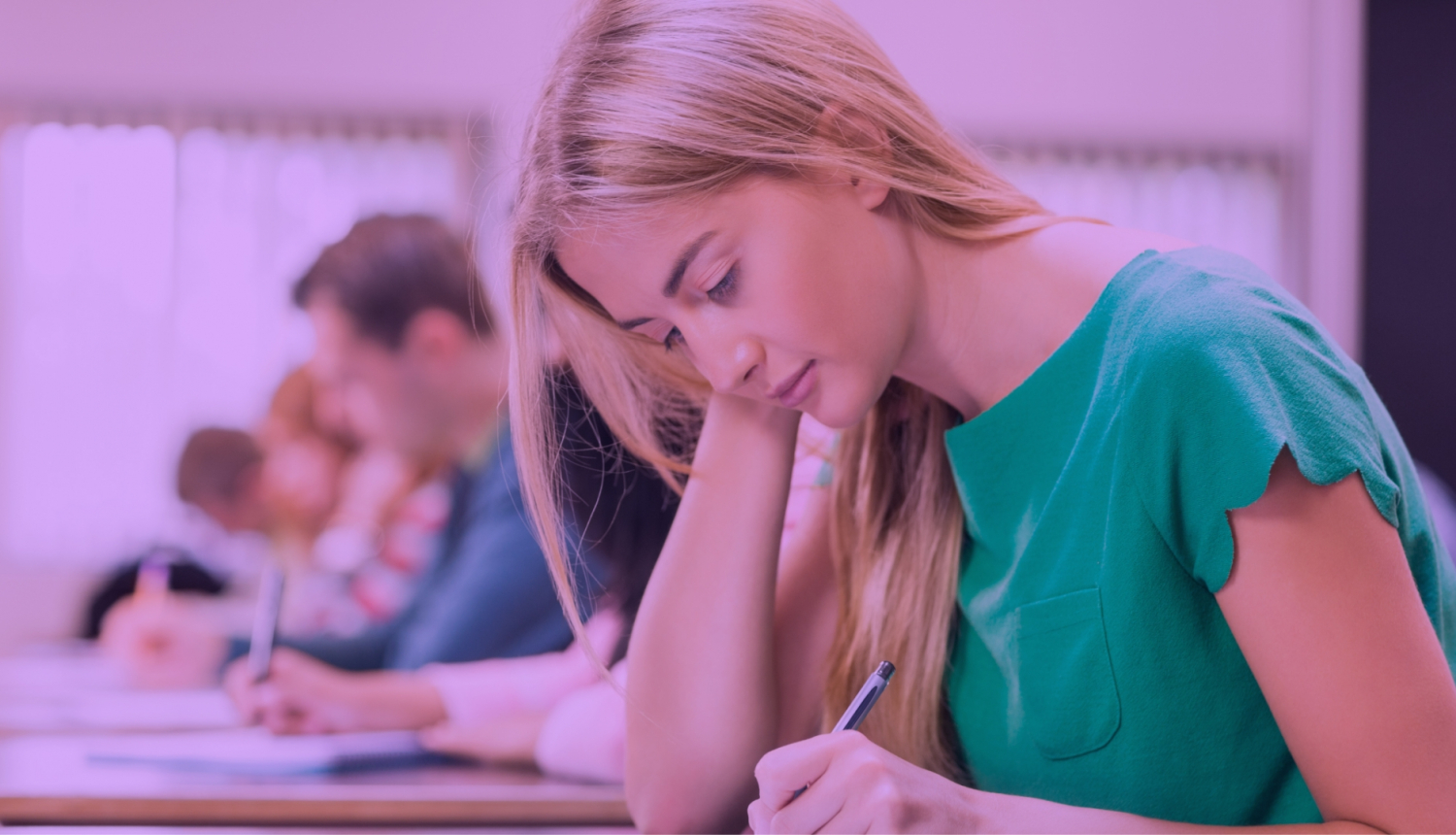 Meitene zaļā apģērbā raksta eksāmenu