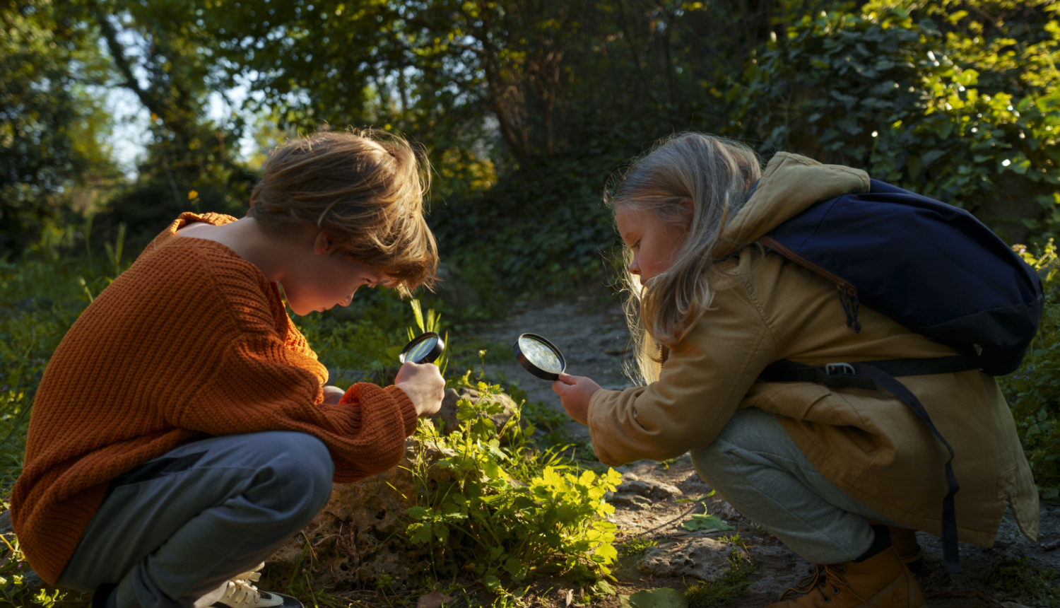 Bērni pēta augu ar lupu