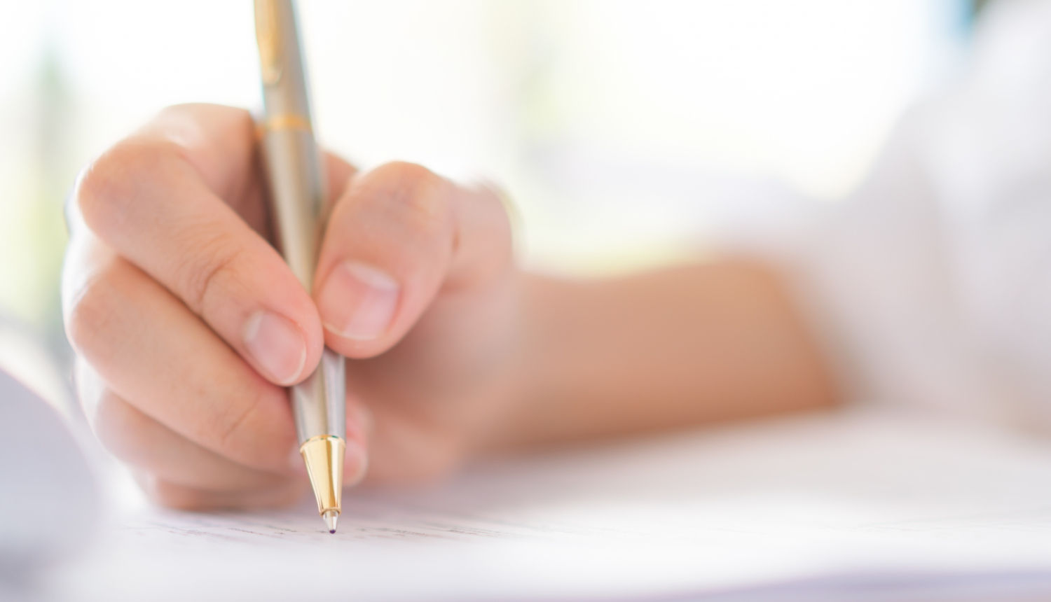 Cilvēka roka tur pildspalvu un raksta