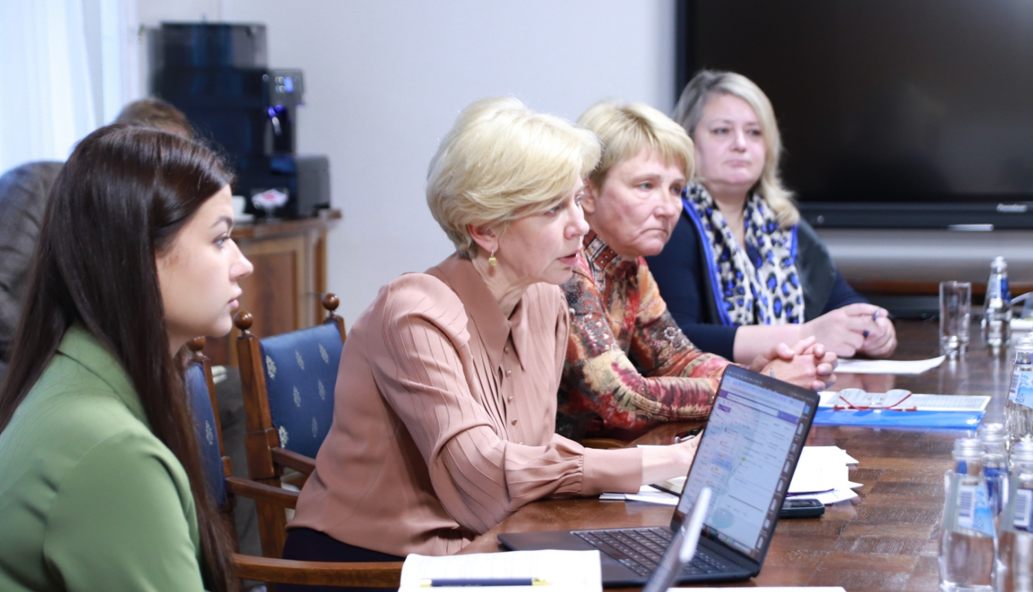 Ministre Anda Čakša sēž pie galda un sarunājas ar sporta skolotājiem