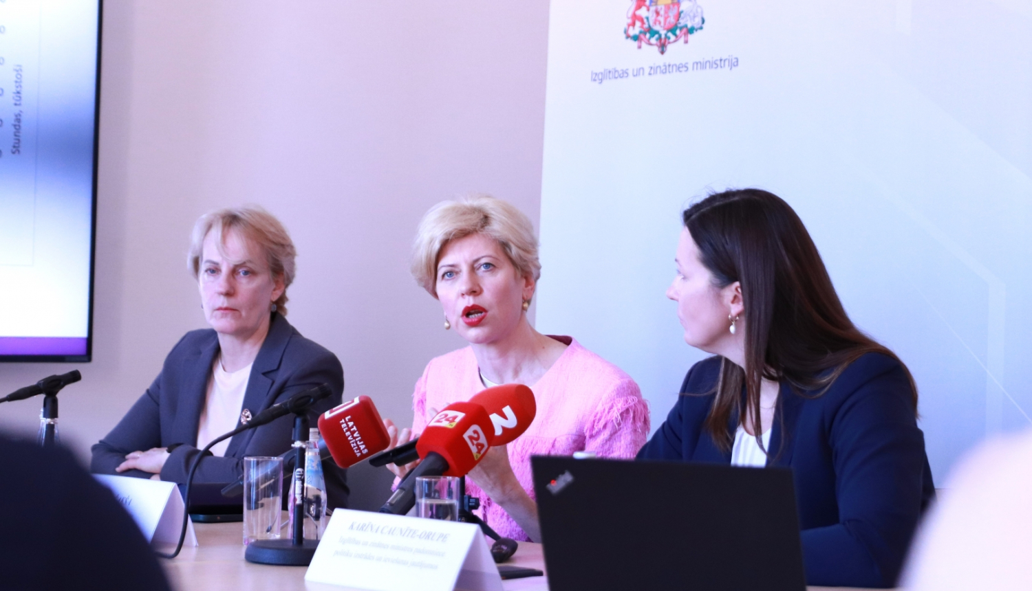 Preses konferencē pie galda sēž izglītības un zinātnes ministre Anda Čakša, IZM Pieaugušo un profesionālās izglītības departamenta direktore Baiba Bašķere un izglītības un zinātnes ministres padomniece politiku izstrādes un ieviešanas jautājumos Karīna Caunīte-Orupe