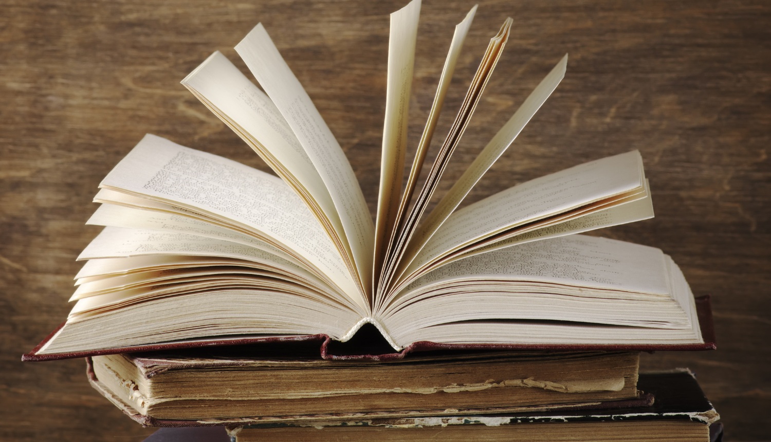 Vairākas vecas grāmatas, augšējā ir atvērta