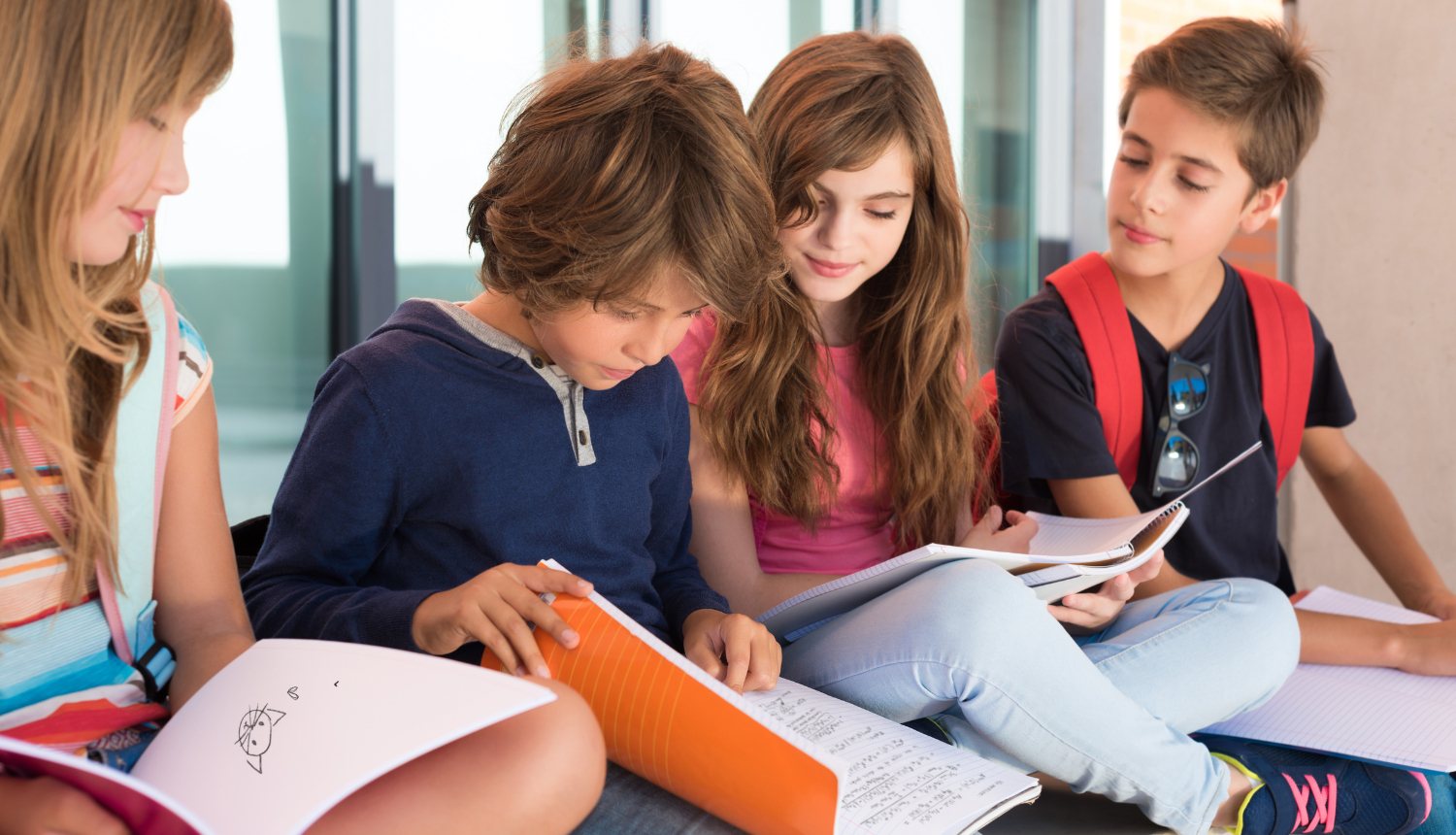 Četri bērni sēž un skatās burtnīcās