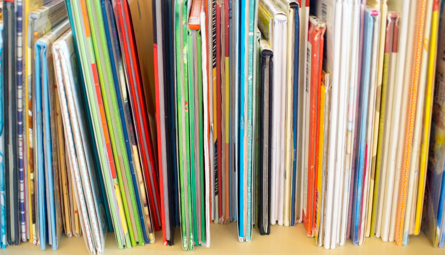 Daudz plānu, krāsainu grāmatu plauktā