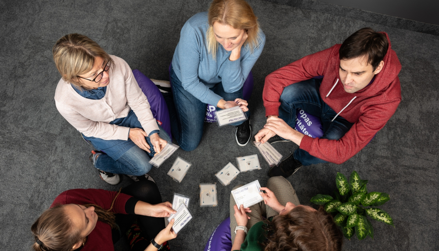 Skats no augšas: četras sievietes un viens vīrietis sēž uz sēžammaisiem un sarunājas