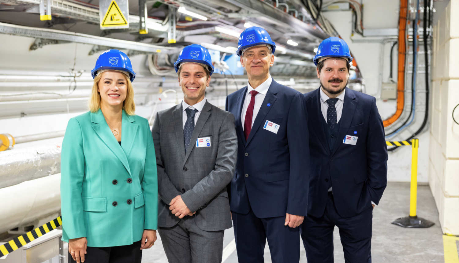 Premjerministre Evika Siliņa un citi Latvijas delegācijas pārstāvji zilās kiverēs stāv CERN telpās.