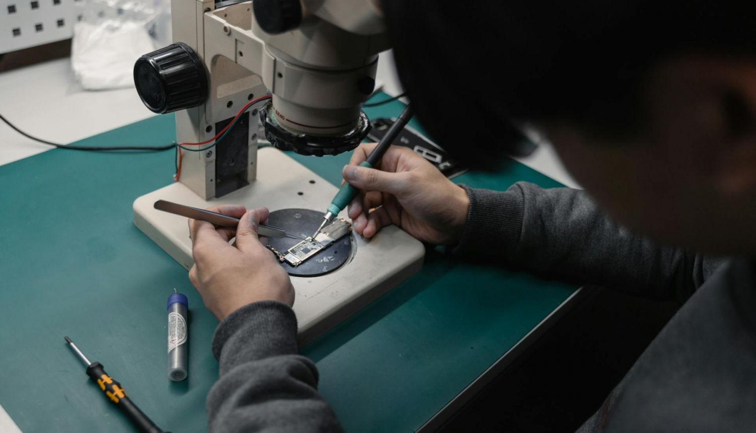 Cilvēka rokas zem mikroshēmas lodē mikroshēmu