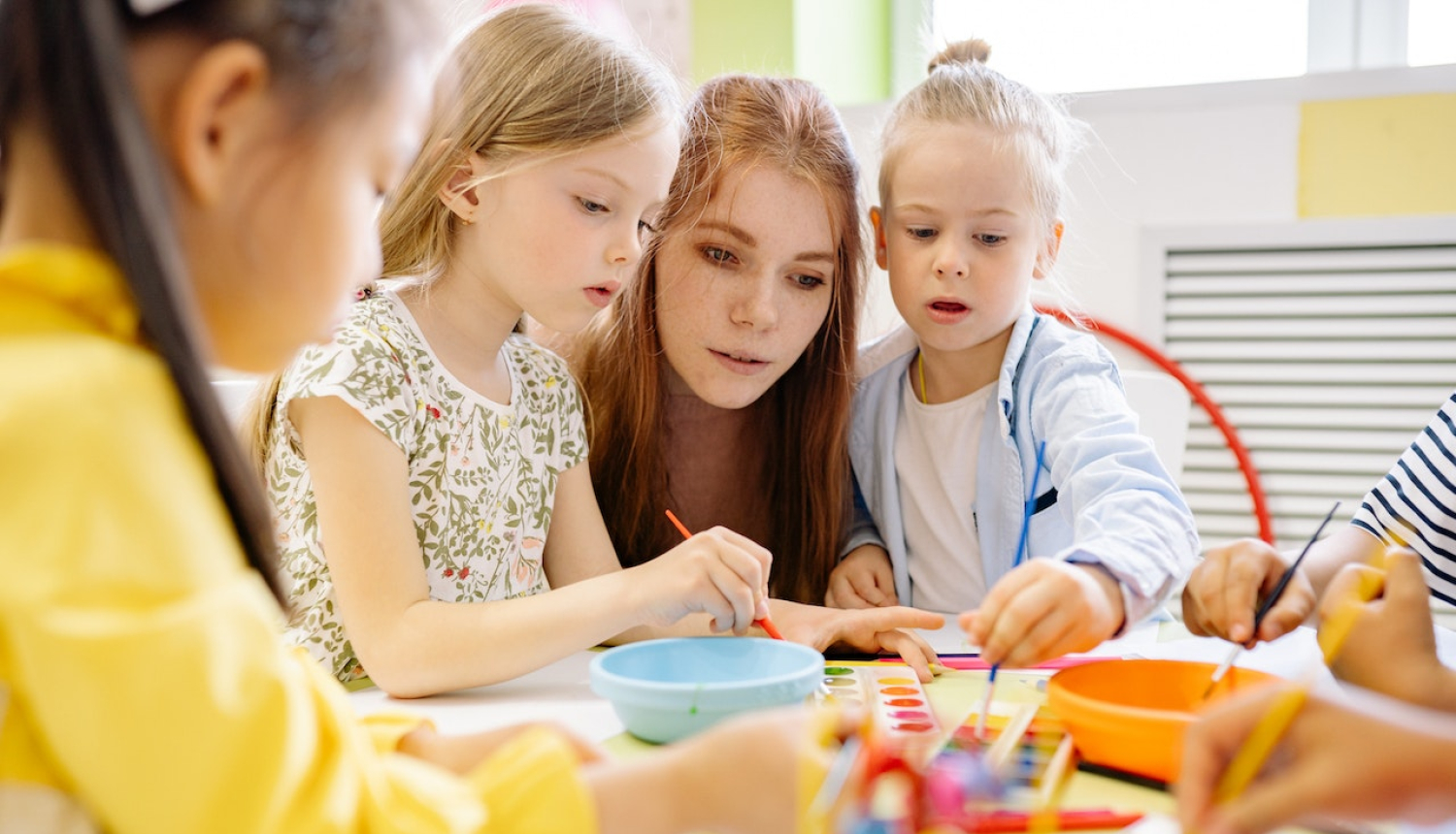 skolotāja ar bērnudārzniekiem darbojas ar rokdarbiem