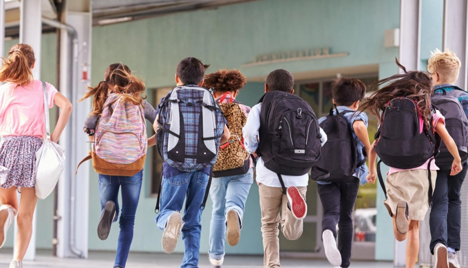 bērni skrien pa skolas gaiteni