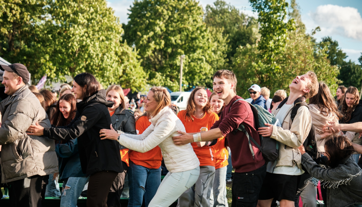 Priecīgi jaunieši spēlē spēli, kurā ar rokām turas viens pie otra 