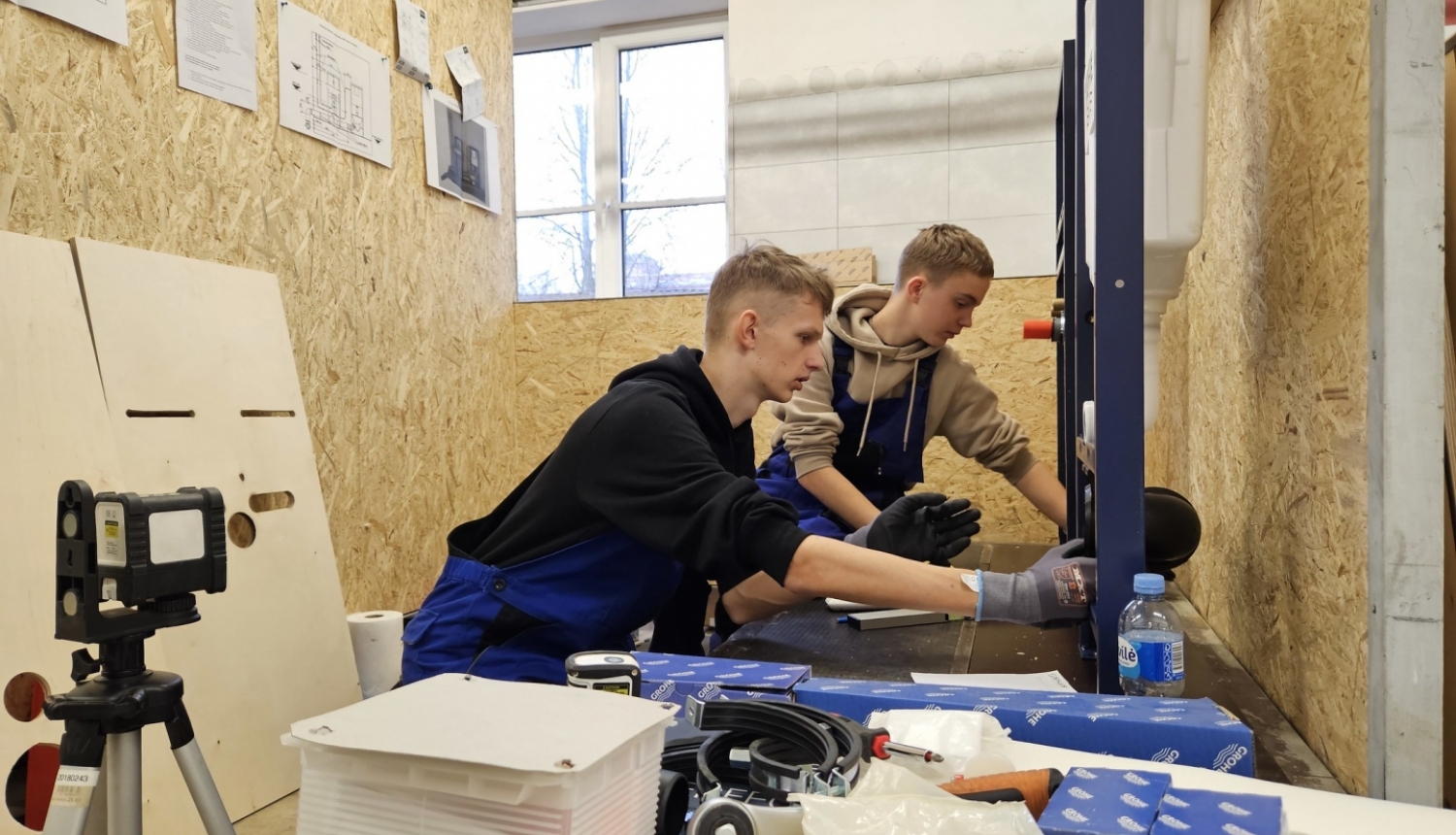 Divi puiši skrūvē instalāciju, apkārt skaidu plākšņu sienas