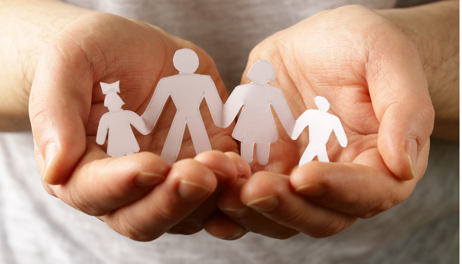 Rokas tur no papīra izgrieztus cilvēciņus, kas simbolizē ģimeni