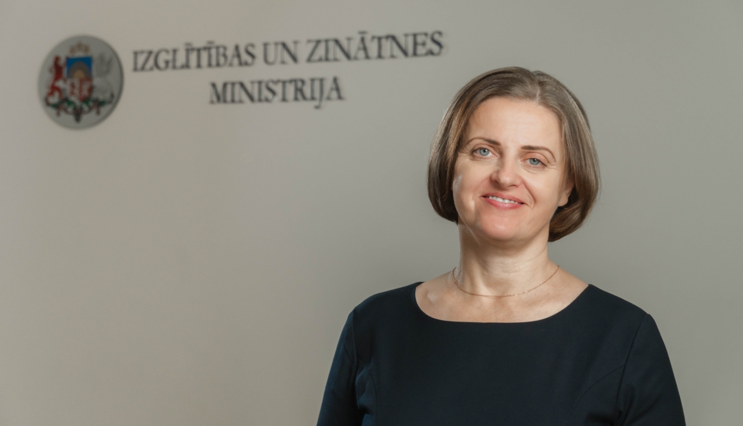 Edīte Kanaviņa, fonā Izglītības un zinātnes ministrijas logo